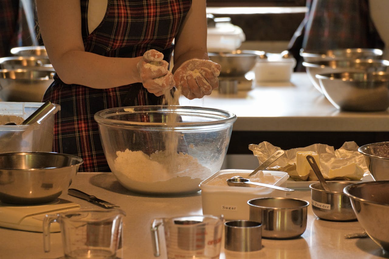 service-01 Close-up of a woman mixing ingredients in a bowl during a baking class with various kitchenware.