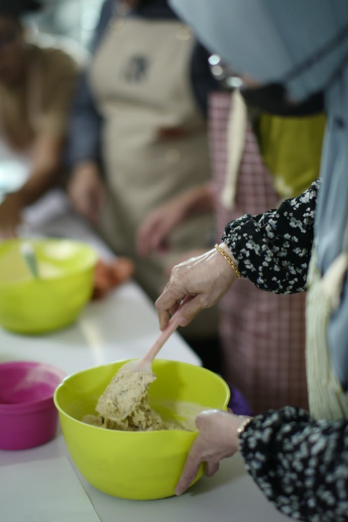 who-we-are Women mixing dough during a baking class in Malaysia, hands-on learning.